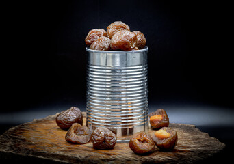 Flavored preserved chinese plums (Preserved fruits) in tin can on dark background. Its flavour has...