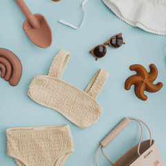 Set of stylish natural Scandinavian nordic baby kids beach toys and clothes on pastel blue background. Baby girl stuff for playing on beach. Flat lay, top view