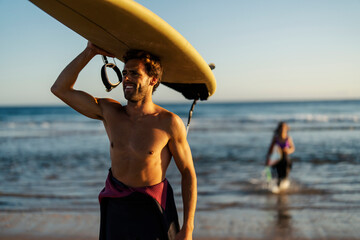 A guy on a beach going surfing.