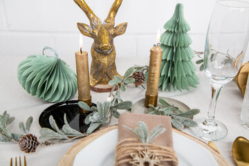 Weihnachtlich gedeckter Tisch mit Hirsch in grün, weiß und gold