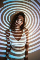 young adult woman or teenager girl in trendy outfit in dark room with projected geometrical...