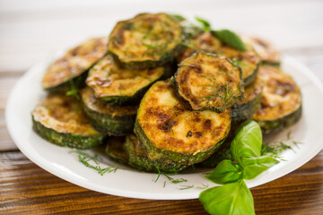 zucchini fried in circles with spices and herbs, in a plate .