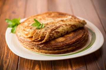 lot of pancakes thin pancakes in a plate, on wooden table.
