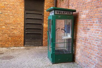 Telephone booth from communism-era next to brick wall, Warsaw, Poland - June 30, 2023