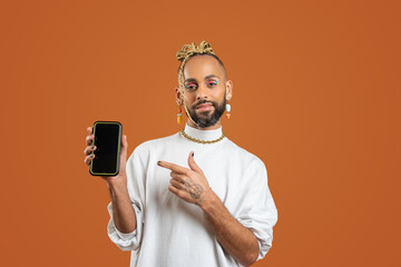 Black latin gay man with smartphone isolated on orange background - obrazy, fototapety, plakaty