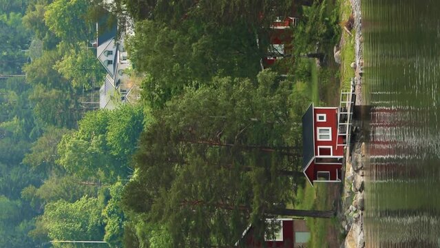 Red Scandic Wooden Sauna Logs Cabins Houses On Island Coast In Summer Cloudy Day. Nordic Architecture. Vertical Footage Video Hyperlapse. Scandinavian Culture And Nature. Travel Concept To Sweden.