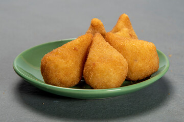 traditional fried coxinha in plate on slate background, popular brazilian snack