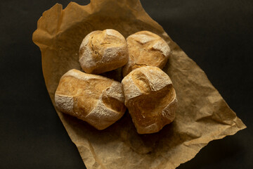 Closeup of home made bread on brown paper and black background. Agricultural feel
