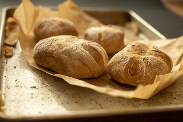 Closeup of home made bread on brown paper in a tray. Dark minimalist food - 622297587