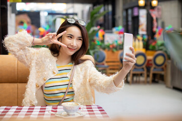 Cheerful young Chinese woman taking selfie with smart phone