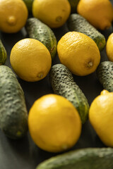 Closeup of yellow lemons and green cucumbers on dark background - 622297706