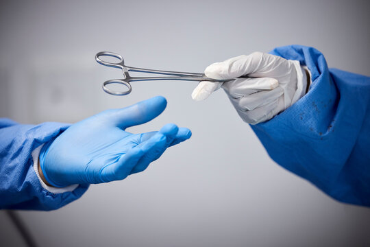 Surgery, hands or doctors with scissors with medicine or surgical procedure or healthcare in hospital. People, medical safety tools or closeup of surgeon in gloves helping in operating room in clinic