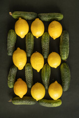 Flat lay with yellow lemons and green cucumbers on dark background - 622298129
