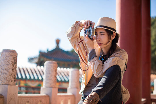 Cheerful young Chinese woman taking photos outdoors