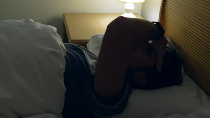 Man waking up in the early morning hours. Person turning bedside lamp light ON starting the day