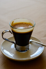 Small glass cup of black arabica coffee served in cafe, close up
