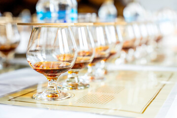 Close up of row transparent covered drinking glasses with rum on the tasting placemats with copy...