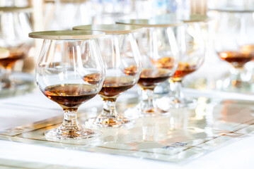 Close up of row transparent drinking glasses with rum on the tasting placemats. Event for connoisseurs of blended old aged strongest liquors