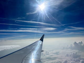 wing of an airplane in the air with a blue background with clouds.