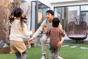 Happy little Chinese children and their father playing in the courtyard