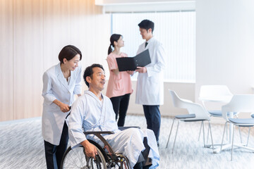 病院で車椅子に乗った入院患者と話す医者
