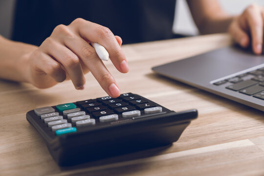 Hand using calculator to calculate income expenses and plans for spending money on home.