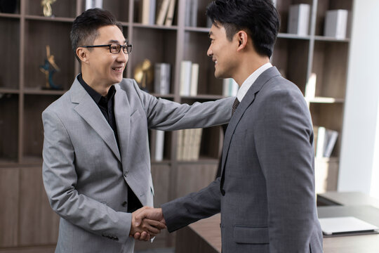 Successful Chinese business people shaking hands in office