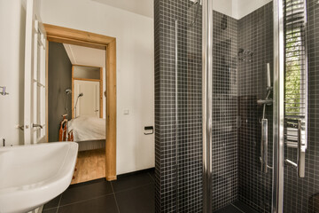 a bathroom with black tiles and wood trim around the shower stall, while it's not visible in this photo