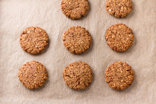 Healthy oatmeal cookies with dates, nuts and flaxseed on baking paper, top view. Delicious homemade vegan baking