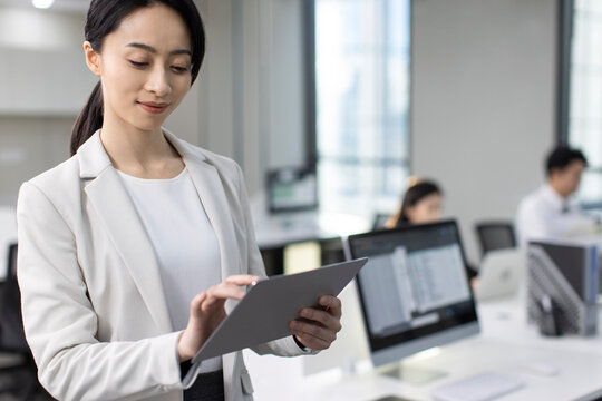 Successful Chinese Businesswoman Using Digital Tablet In Office