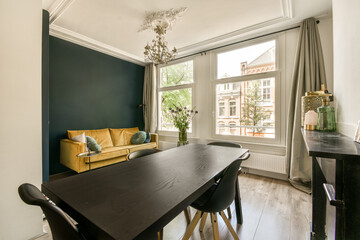 a living room with blue walls and white trim on the ceiling, wooden table and chairs in front of the window