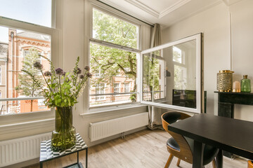 a living room with a table, chairs and flowers in a vase on the window sicfgd