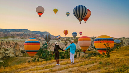 Kapadokya Cappadocia Turkey, a happy young couple during sunrise watching the hot air balloons of...