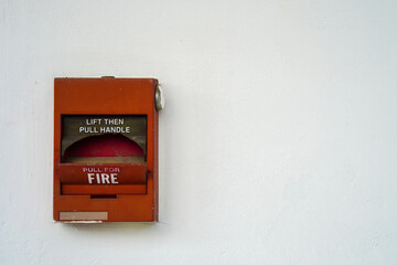 Broken red fire alarm box against clean white wall with copy space for text