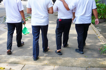 Four men in white shirts strolling together as friend. No face. Companionship of four men in white shirts walking together