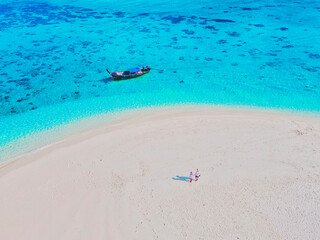 Fototapeta na wymiar a couple of men and women at a white sandbank in the ocean of Koh Lipe Island Southern Thailand, with turqouse colored ocean and white sandy beach sandbar at Ko Lipe on a sunny day