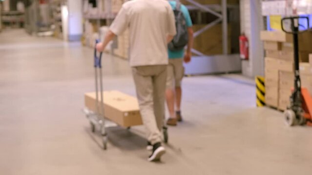 blurred man carries large shopping trolley in self-service furniture store, shopping goods DIY and Home Improvement, individuals stack and transport furniture for projects, Budget-Friendly Shopping