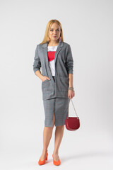 Blonde woman in elegant casual plaid office clothes with a handbag on a chain