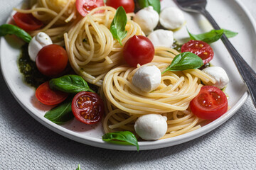 Spaghetti with mozzarella, tomatoes, basil and pesto sauce. Pasta Caprese