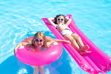 happy little girls swim in the pool in summer in sunglasses, space for text