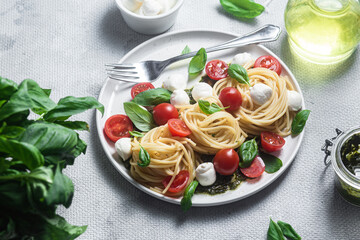 Spaghetti with mozzarella, tomatoes, basil and pesto sauce. Pasta Caprese