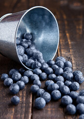 Blueberries in small steel bucket on grunge wooden board. Natural healthy food