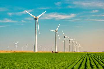Windmill Park with a blue sky and green agricultural field, and windmill turbines park in the...