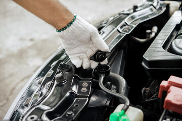 Close-up of hand of a gloved mechanic opening the radiator cap to check the coolant level. A man's...