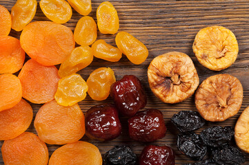 Dried fruits scattered on a wooden background. Top view. Candied fruits, lemon, apricot, fig and...