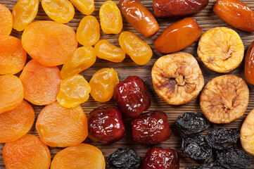 Dried fruits scattered on a wooden background. Top view. Candied fruits, lemon, apricot, fig and dates.
