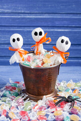 Halloween candy bucket, lollipop ghosts and rubber spider on purple wooden backround,  vertical orientation