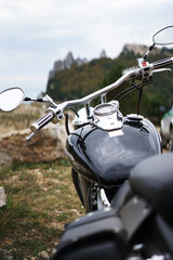 A black classic motorcycle stands against the background of mountains and gray sky