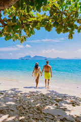 a couple of men and woman on the beach of Koh Kradan Island Thailand, men and women relaxing on the beach with a turqouse colored ocean on a sunny day © Fokke Baarssen