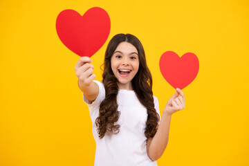 Lovely romantic teenage girl hold red heart symbol of love for valentines day isolated on yellow background. Happy teenager, positive and smiling emotions of teen girl.